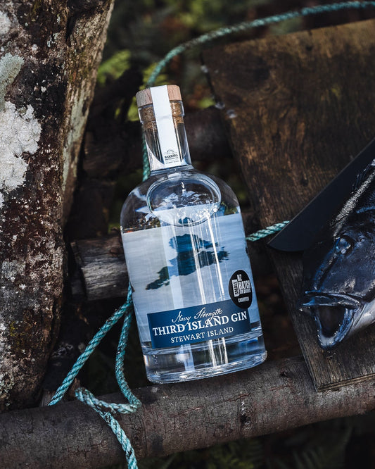 Bottle of Third Island Navy Strength Gin on a rustic wooden surface with a natural background