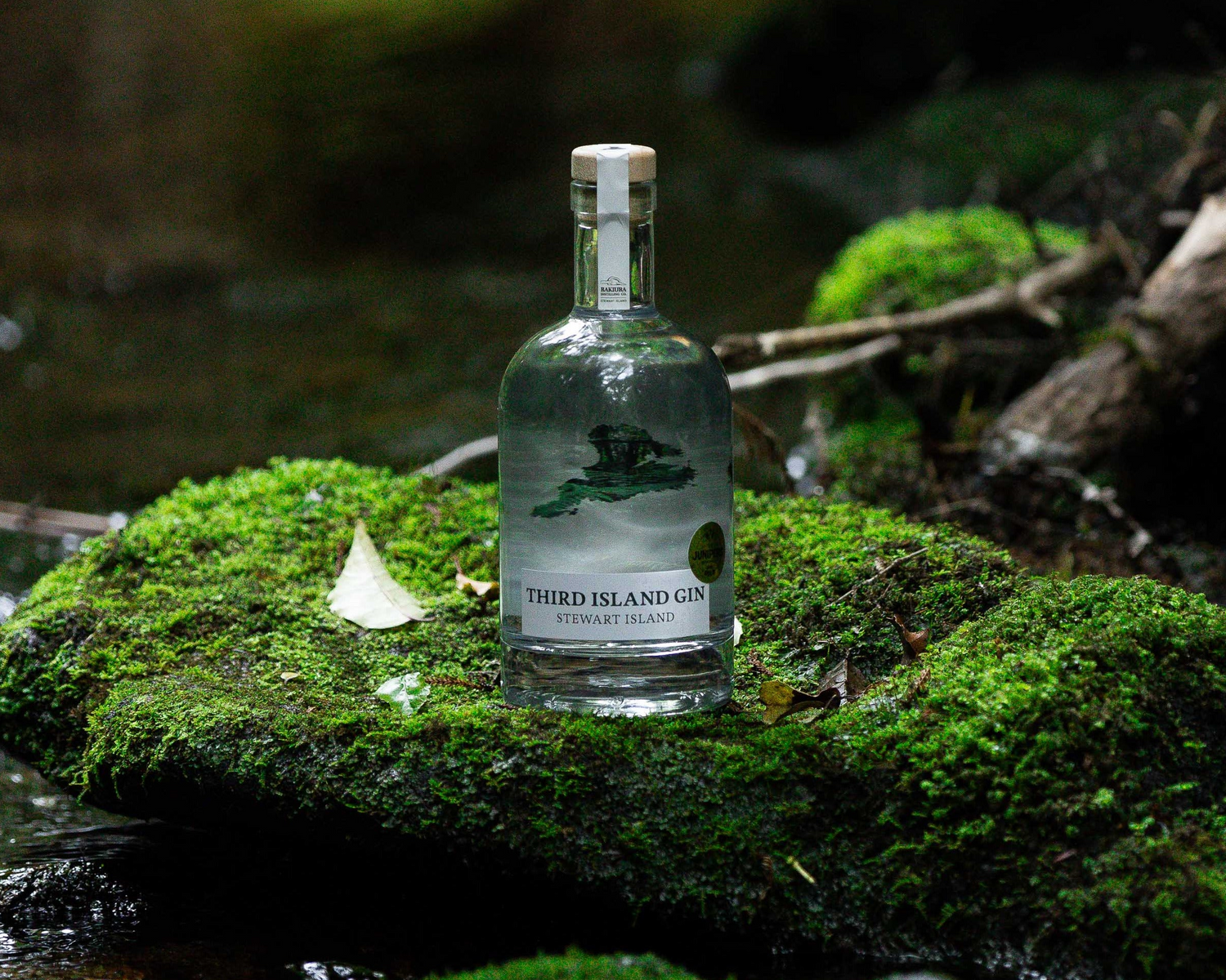 Bottle of Third Island Gin on a mossy rock with a natural background